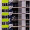 Close-up image of a modern building with balconies featuring a worker on a ladder.